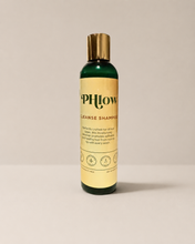 Load image into Gallery viewer, A bottle of PHlow Cleanse Shampoo with a dark green bottle, gold cap, and a beige label, set against a neutral light gray background.